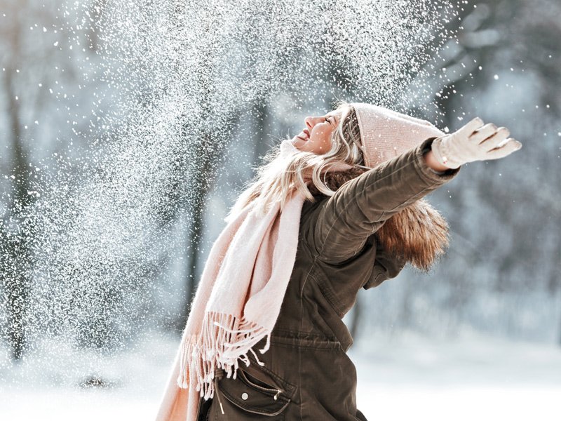 Life Extension, a vital and joyful woman outside on a winter day throwing snow in the air